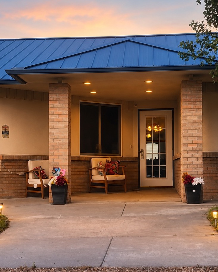 Covered front entrance and porch at Your Home Wiggins at dusk
